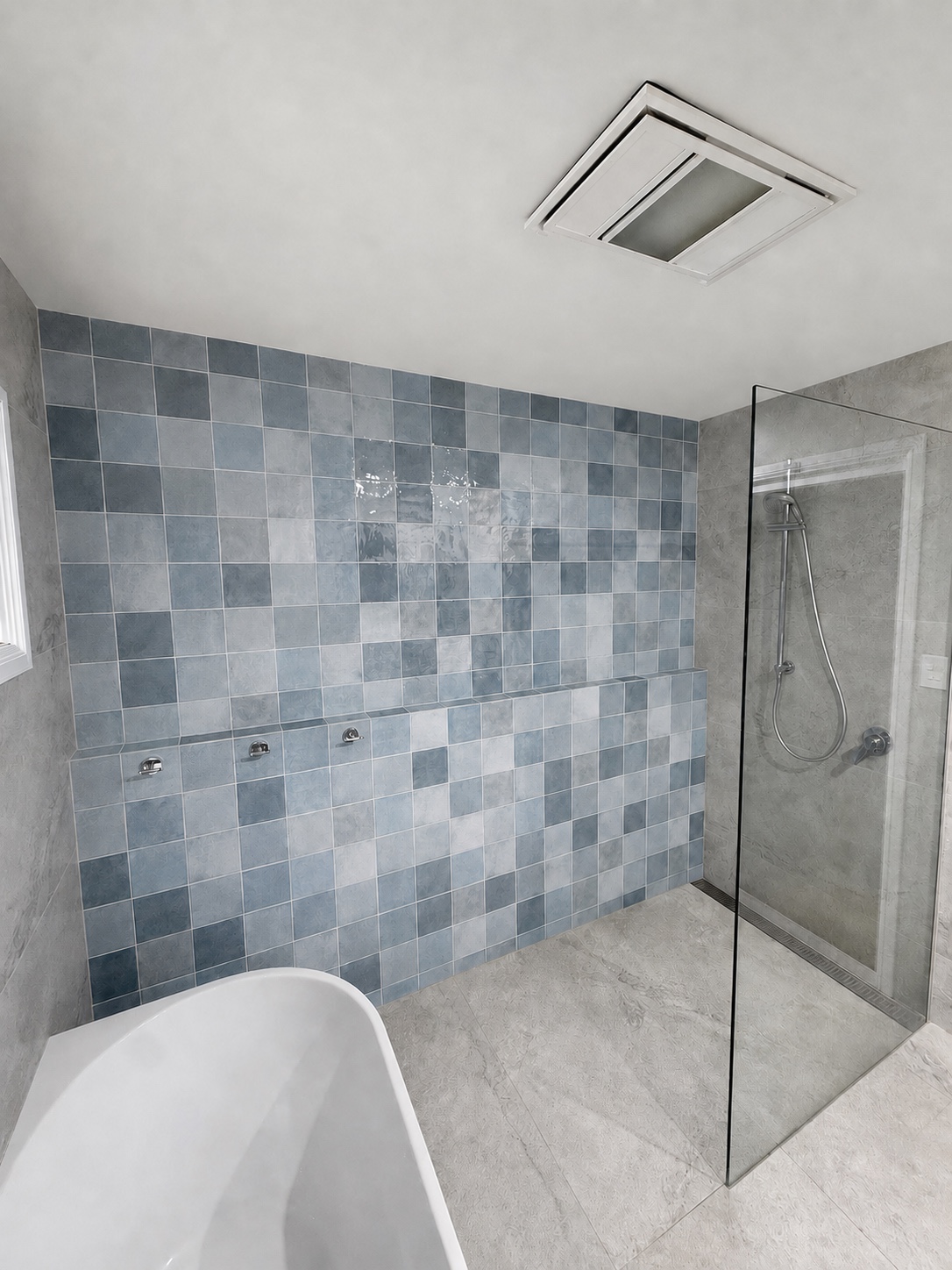 Bathroom with a small-format blue-grey tiled feature wall, large-format stone-look tiles, an open shower and an integrated tiled ledge