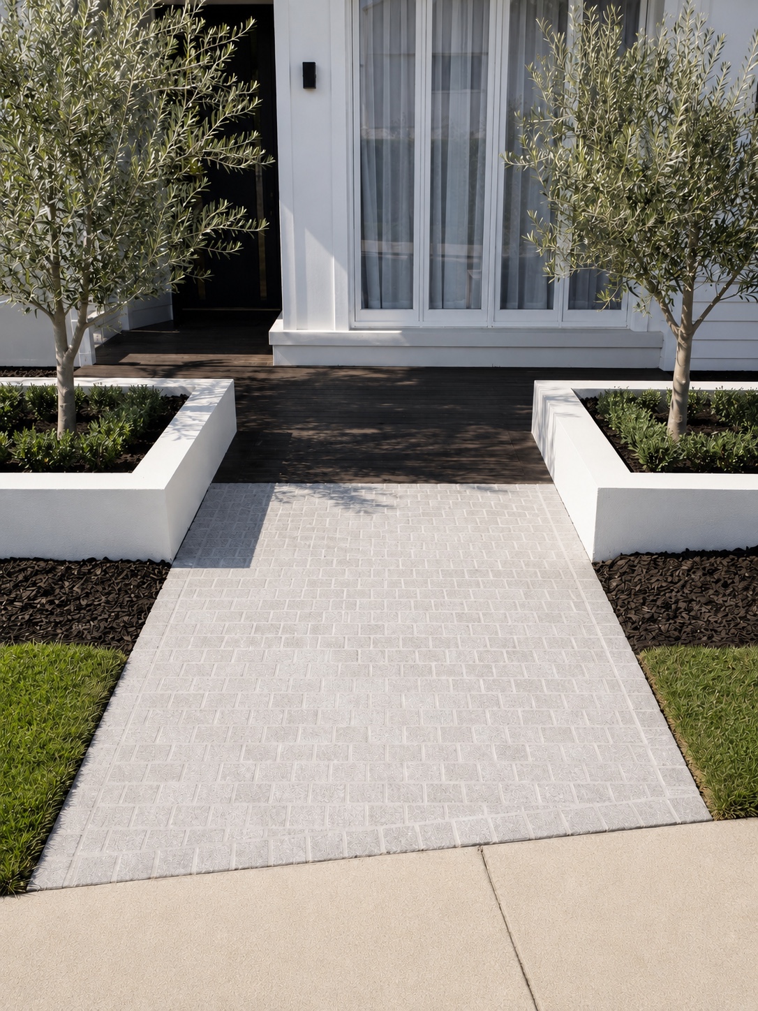 Light cobblestone paved entry leading between landscaped planter boxes to the front of a home