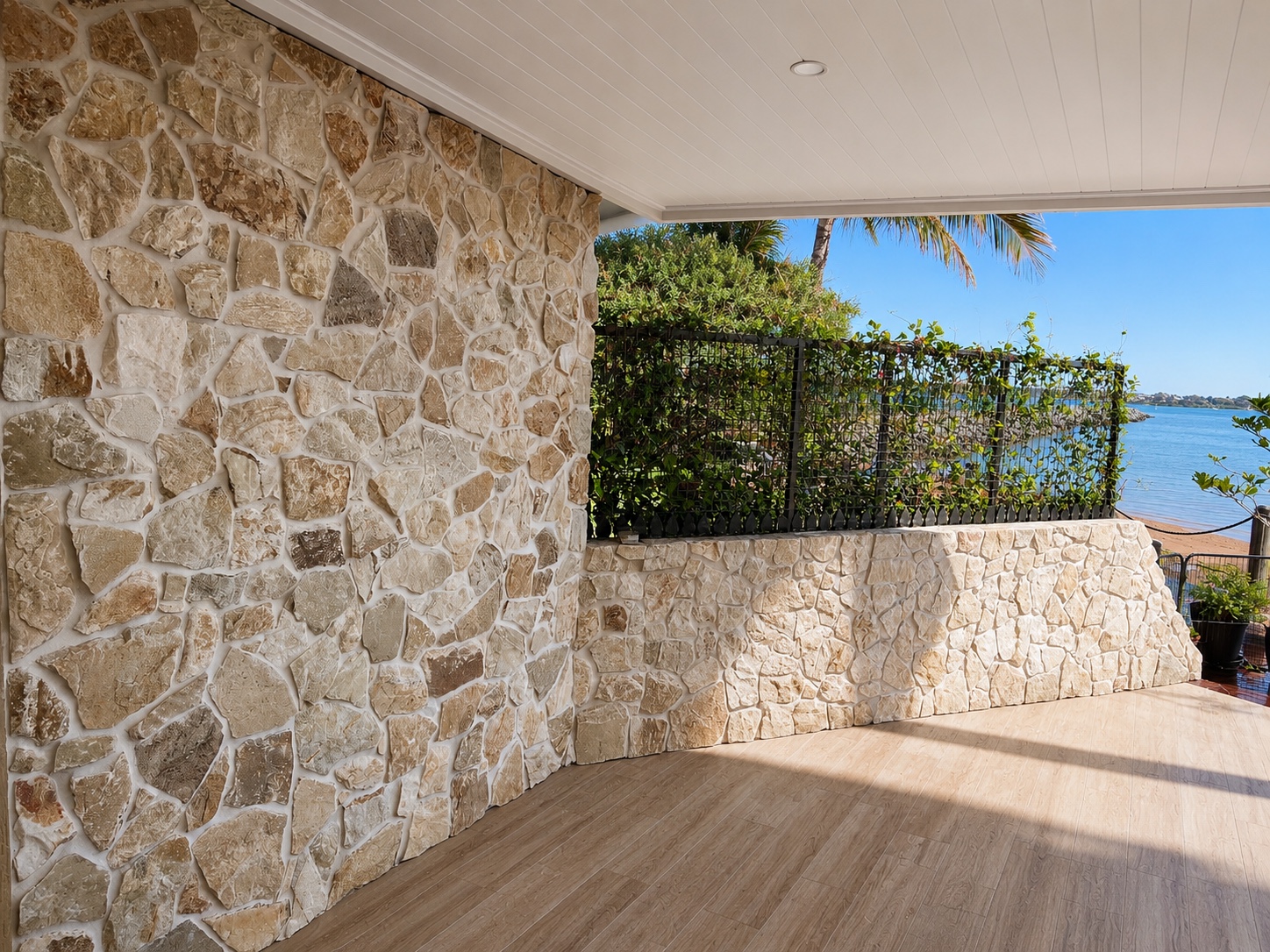 Outdoor entertaining area finished with loose-form grouted stone walls and timber-look floor tiles